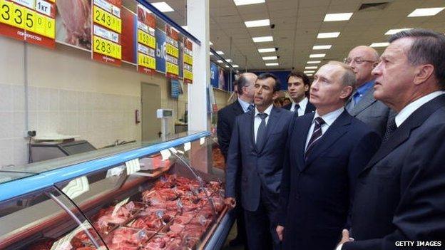 Russian President Vladimir Putin (2R) looking at prices inside a Perekrestok supermarket in Moscow