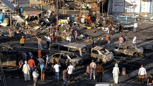 Iraqi civilians gather the morning after a string of car bombs tore through busy shopping streets in several neighbourhoods in Baghdad, Iraq, Thursday, Aug. 7, 2014.