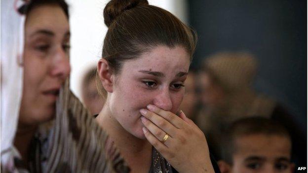 An Iraqi Yazidi woman who fled the violence in the northern Iraqi town of Sinjar, cries as she stands among others at a school where they are taking shelter in the Kurdish city of Dohuk, 05/08/14