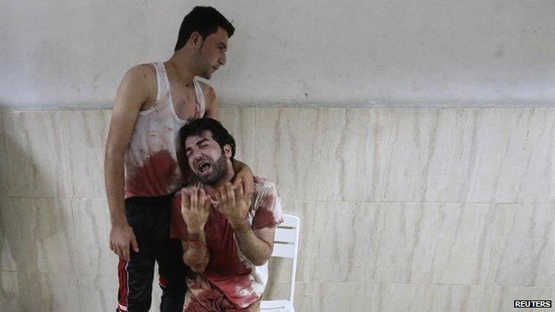 A bloodstained man mourns his father in Khan Younis, 23 July, Reuters