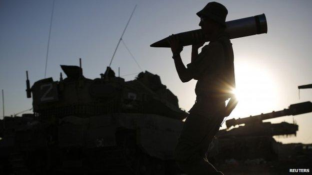 An Israeli soldier carries a tank shell in a staging area near the border with the Gaza Strip (7 August 2014)