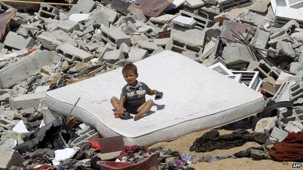 A Palestinian child sits on a mattress on the rubble of a house which was destroyed in an Israeli air strike on Abasan, east of the southern Gaza Strip town of Khan Yunis and close to the border with Israel (7 August 2014)