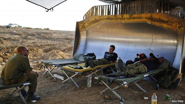 Israeli soldiers rest at a staging area near the border with the Gaza Strip (7 August 2014)