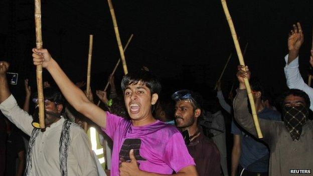 Supporters of Tahirul Qadri, leader of political party Pakistan Awami Tehreek (PAT), chant slogans as they wave sticks during a protest in Lahore 8 August 2014