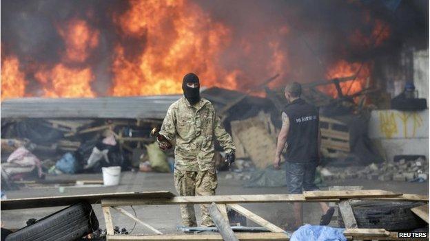 A protester holds a petrol bomb as he tries to prevent municipal workers and volunteers from clearing away barricades and tents at Independence Square in Kiev August 9