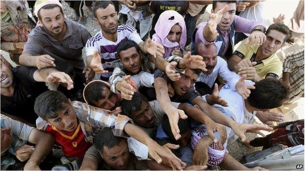 Displaced Iraqis from the Yazidi community gather for humanitarian aid at the Syria-Iraq border