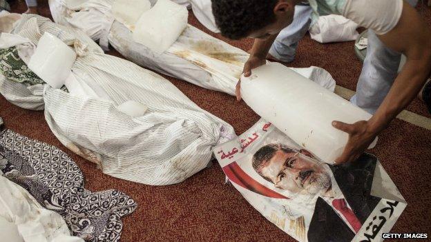 An Egyptian places blocks of ice next to the bodies of victims from the police offensive on the Rabaa protest camp in Cairo - 14 August 2014