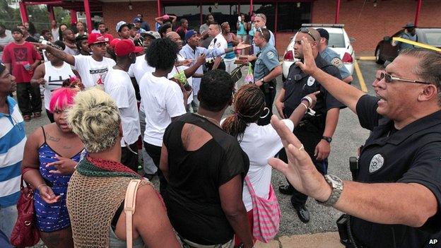 Ferguson police officers try to calm down a crowd near the place where Michael Brown was fatally shot by police in Ferguson on 9 August 2014