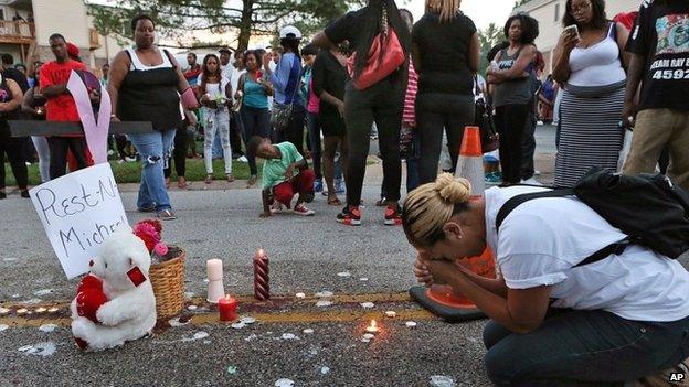 A woman prays at the spot where Michael Brown was killed on 10 August 2014 in Ferguson