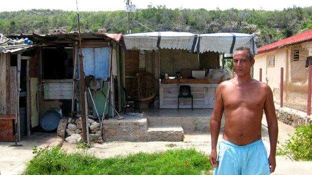 Roberto stands in front of his house ruined by Hurricane Sandy.