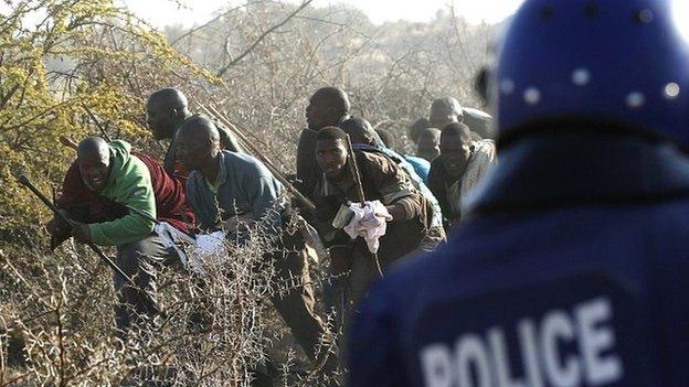 A policeman fires at striking miners at the Marikana platinum mine in South Africa on 16 August