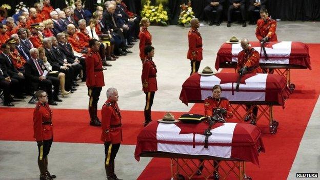 Royal Canadian Mounted Police officers collect possessions from the caskets of three fellow officers who were killed last week during a regimental funeral in Moncton, New Brunswick, 10 June 2014