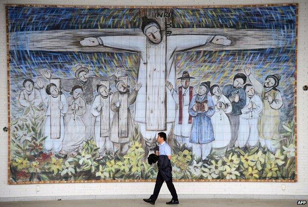 A man passing in front of a huge wall painting for Korea"s Catholic martyrs at Solmoe Shrine in Dangjin (7 August 2014)