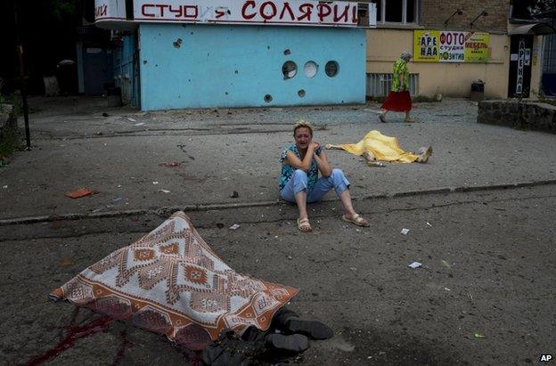 A woman weeps among covered dead bodies after government shelling of Luhansk, eastern Ukraine (18 July 2014)