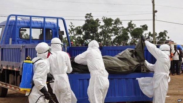 Health workers load the body of a man found on the street, suspected of dying from the Ebola virus, in the capital city of Monrovia, Liberia, 12 August, 2014