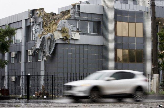 A car passes a shell-damaged building in Luhansk, east Ukraine (8 July 2014)