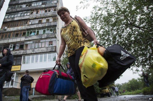 A woman leaves her shell-damaged block of flats in Luhansk, east Ukraine (8 July 2014)