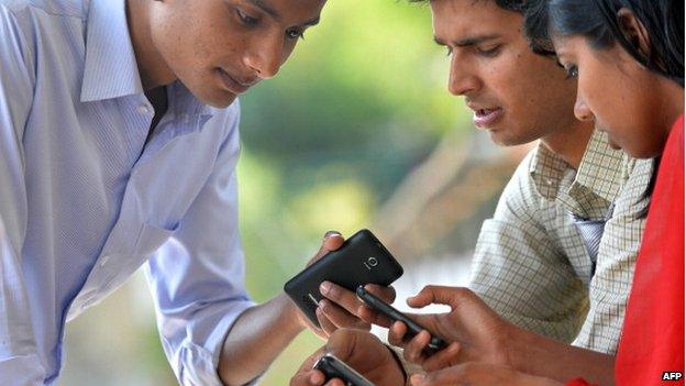 Three young people hold mobile phones