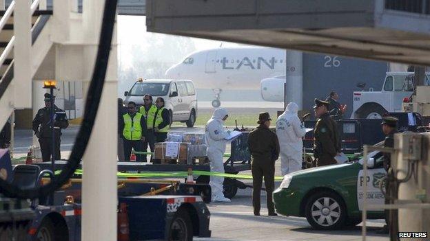 Police inspect the scene where an armoured truck transporting money was robbed at the international airport of Santiago city on 12 August, 2014