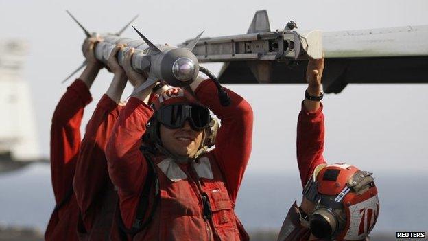 Weapon handlers carry an air to air missile on the aircraft carrier USS George H.W. Bush