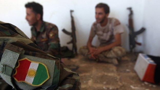 Peshmerga fighters rest with guns