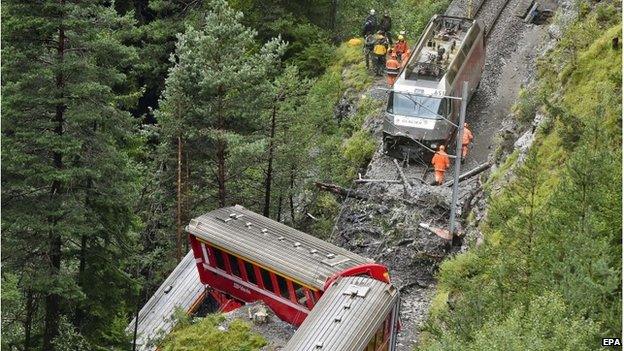 Rescuers work near a train after it was derailed by a landslide near Tiefencastel, in a mountainous part of eastern Switzerland, on August 13, 101