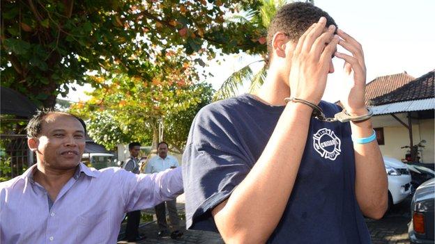 A police officer escorts suspect Tommy Schaffer during an investigation at a police office in Nusa Dua on Indonesian resort island of Bali on 13 August, 2014