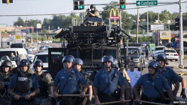 Riot police stand guard as demonstrators angry at the fatal shooting of Michael Brown gather in Ferguson, Missouri - 13 August 2014