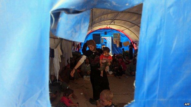 Displaced Iraqi Yazidis, who fled a jihadist onslaught on Sinjar, stand inside a tent after they took refuge at the Bajid Kandala camp in Dohuk province 13/08/2014