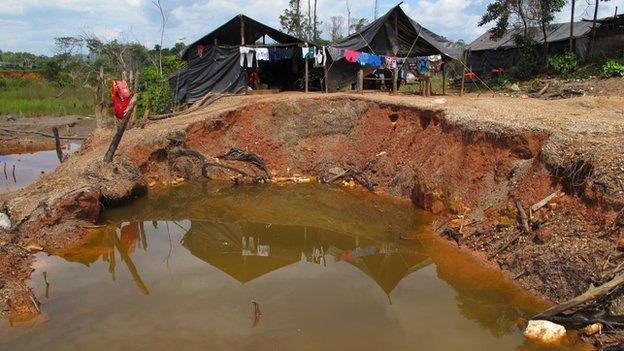 Large pool of brown water with tents in the background