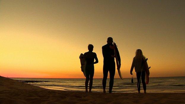 surfers on the beach at dawn