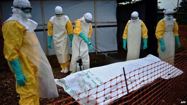 Medecins Sans Frontieres (MSF) medical workers disinfect the body bag of an Ebola victim at the MSF facility in Kailahun, Sierra Leone, 14 August 2014