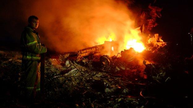 A firefighter stands across the debris of MH17