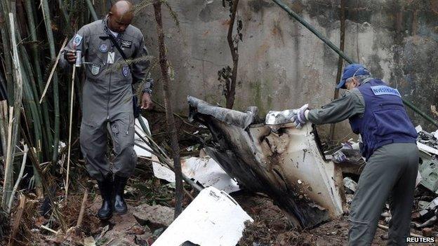 Air force members survey the wreckage site of the crashed private jet, August 14, 2014.