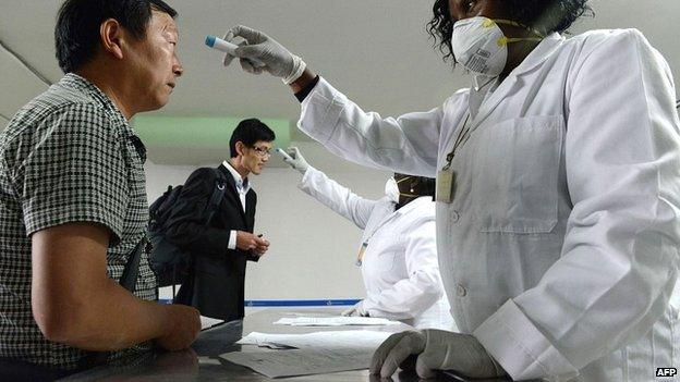 Kenyan health officials take the temperatures of passengers arriving at the Jommo Kenyatta International Airport - 14 August 2014