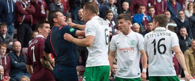 Hibs defender Jordon Forster is held by assistant referee Gavin Harris during a heated exchange with Jamie Walker of Hearts