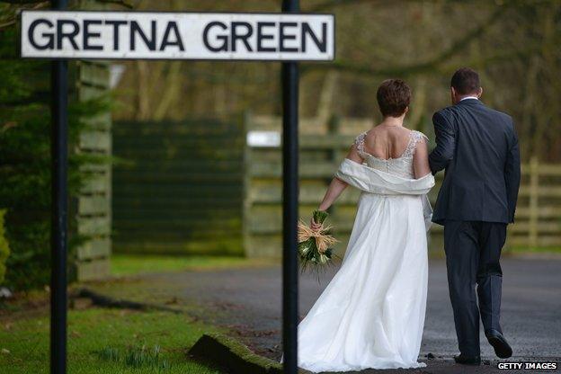 A couple with a Gretna Green sign in the foreground