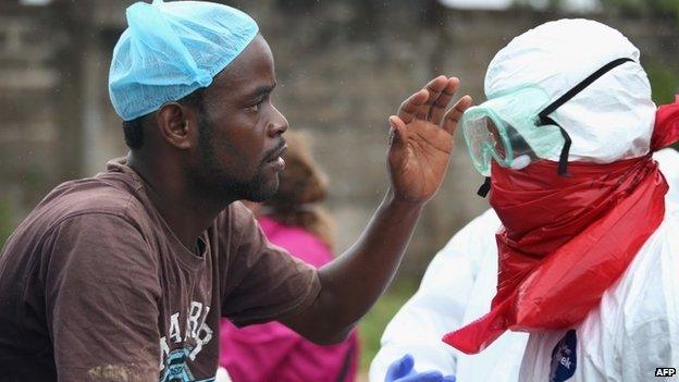 A Liberian burial team carefully puts on protective clothing before retrieving the body of an Ebola victim from his home on 17 August 2014 near Monrovia, Liberia