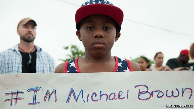 A protestor stands outside a church in Ferguson, Missouri, holding a sign reading "I'm Michael Brown"