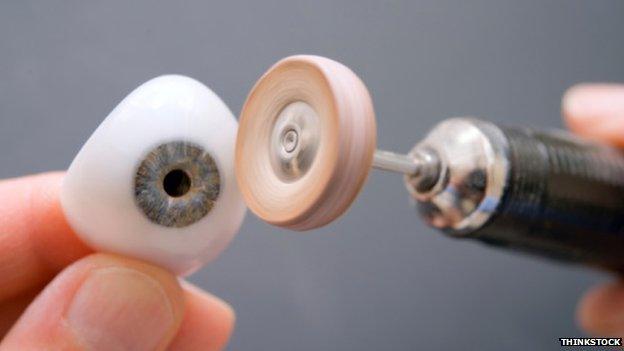An ocular prosthesis being filed down by a small handheld filer