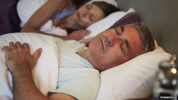 Two people asleep in bed, a man and woman