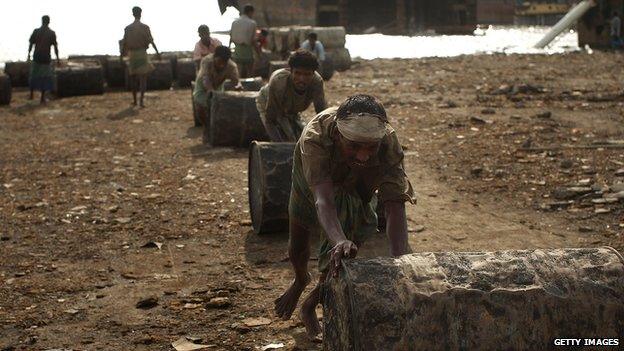 Labourers move oil barrels from a ship being scrapped in the port city of Chittagong, Bangladesh