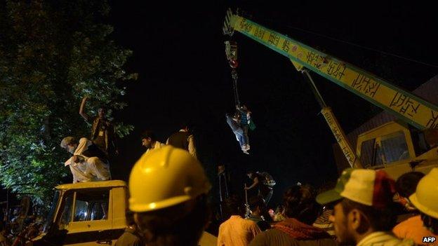 Supporters of Canada-based preacher Tahir-ul-Qadri climb on a crane to remove containers to march towards the parliament as they take part in an anti-government demonstration in Islamabad, 19 August 2014