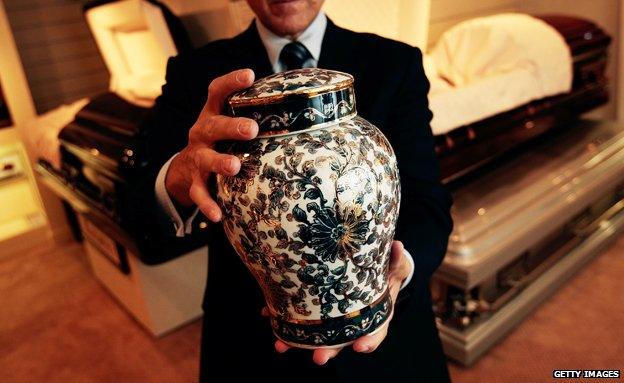 A man holds an ornate urn