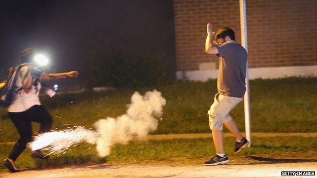 Police lob tear gas at people walking near a protest over the killing of teenager Michael Brown