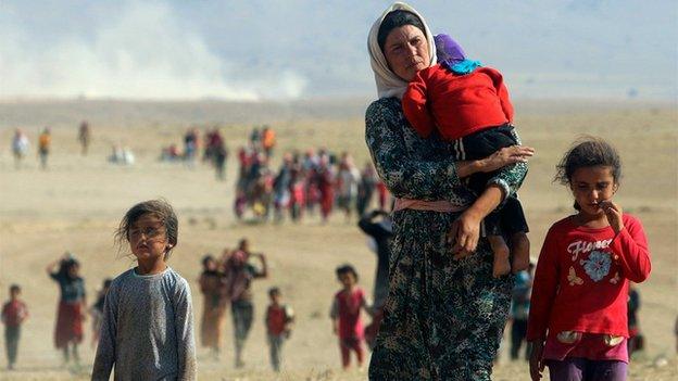 Displaced people from the minority Yazidi sect walk towards the Syrian border, on the outskirts of Sinjar mountain