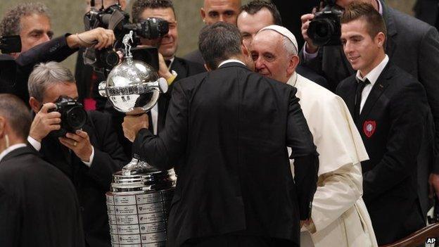 Pope Francis greets San Lorenzo football team players holding the Copa Libertadores they won last week at the Vatican on 20 August, 2014