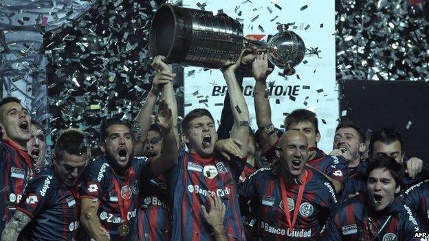 San Lorenzo players hold up the trophy after winning the Copa Libertadores 2014 final second leg football match against Nacional in Buenos Aires on 13 August, 2014