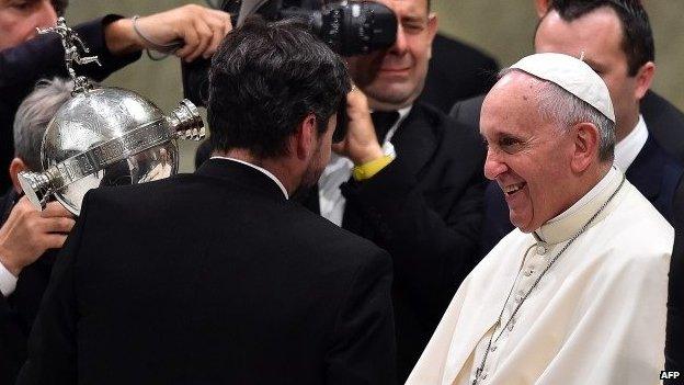 Pope Francis greets San Lorenzo football team players holding the Copa Libertadores they won last week at the Vatican on 20 August, 2014