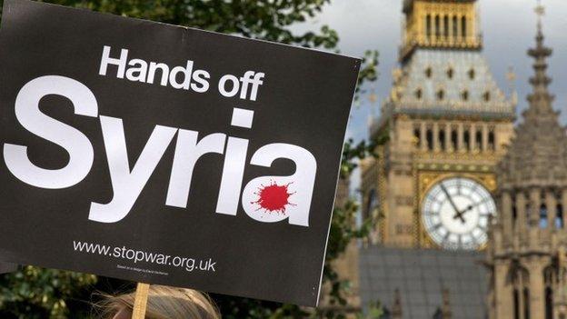 Demonstrators hold up placards during a protest against potential British military involvement in Syria at a gathering outside the Houses of Parliament